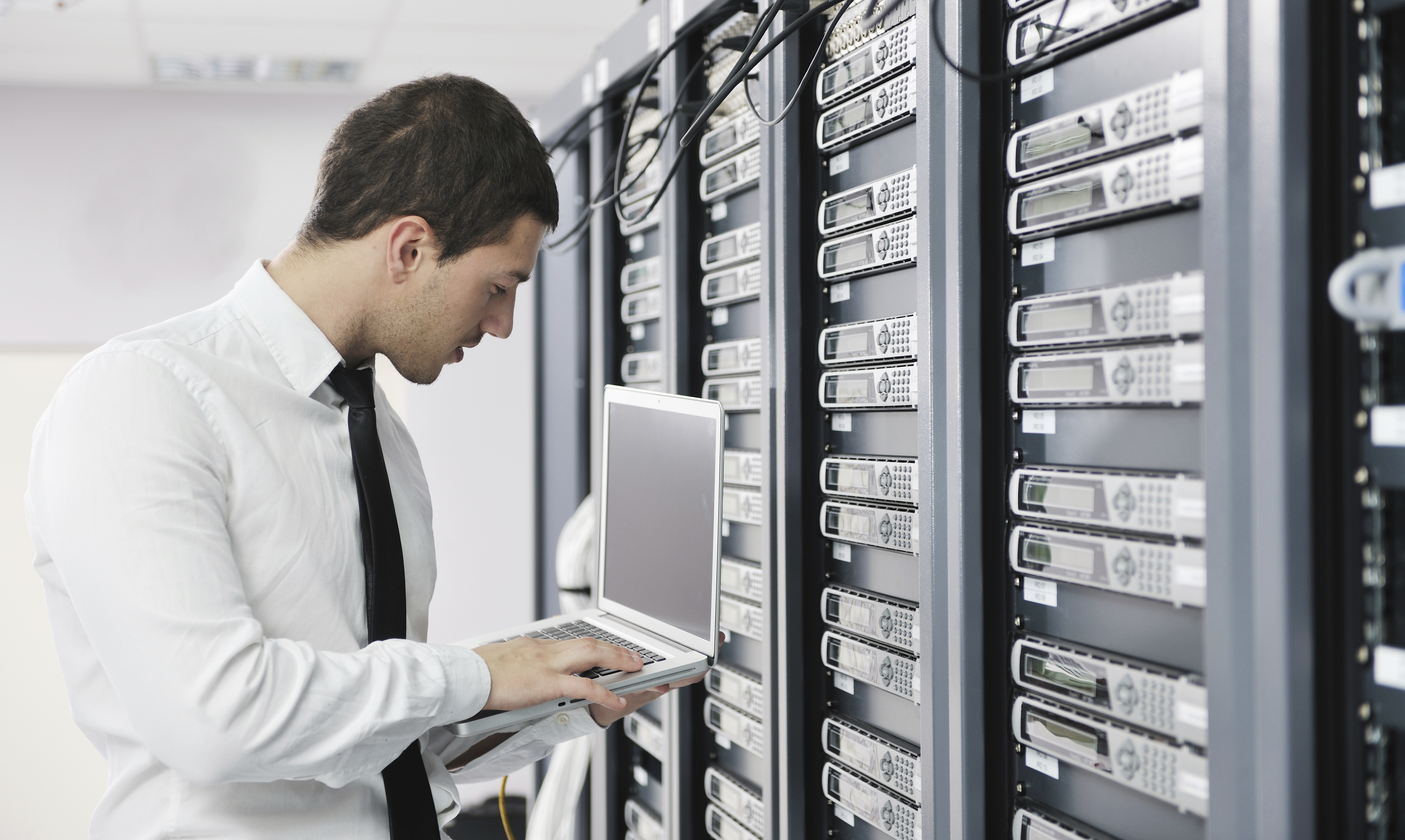 young engeneer business man with thin modern aluminium laptop in network server room